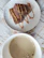 Close-up of a freshly baked brownie with a cup of coffee on a rustic wooden table.