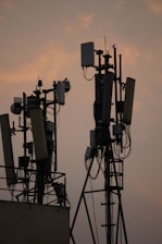 Close-up of technicians installing antennas on a communication tower at sunset.