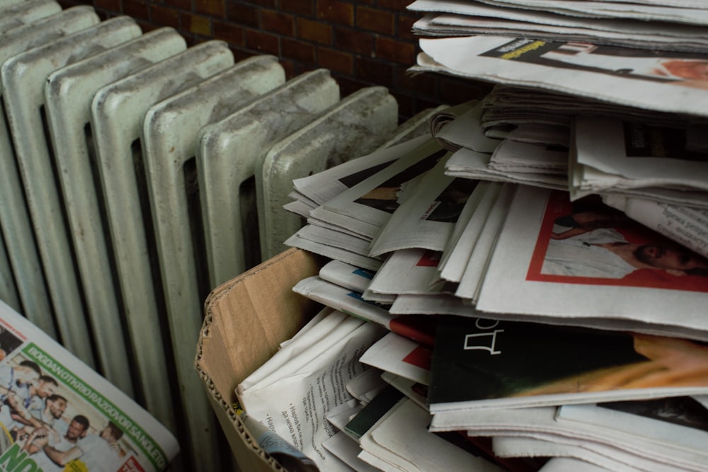 a pile of newspapers sitting next to a radiator