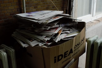 a cardboard box filled with newspapers next to a radiator