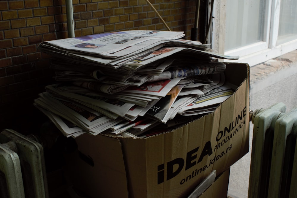 a cardboard box filled with newspapers next to a radiator
