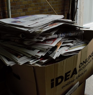 a cardboard box filled with newspapers next to a radiator