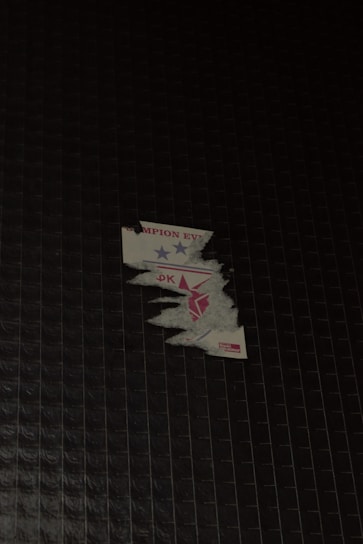 Close-up of a hand peeling a vibrant sticker from its backing paper.