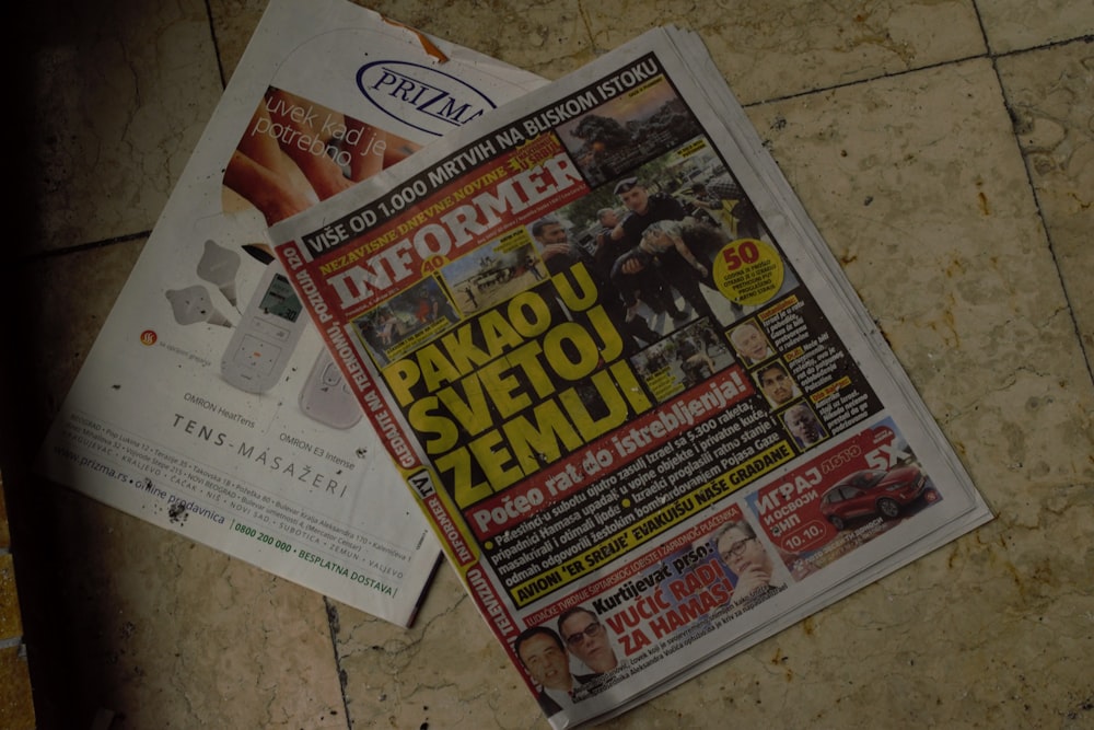 a pile of newspapers sitting on top of a tiled floor