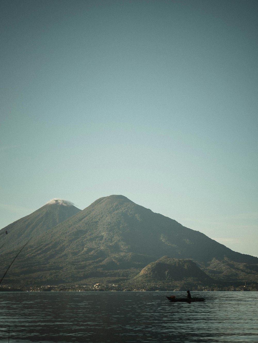 a person in a boat on a lake with a mountain in the background