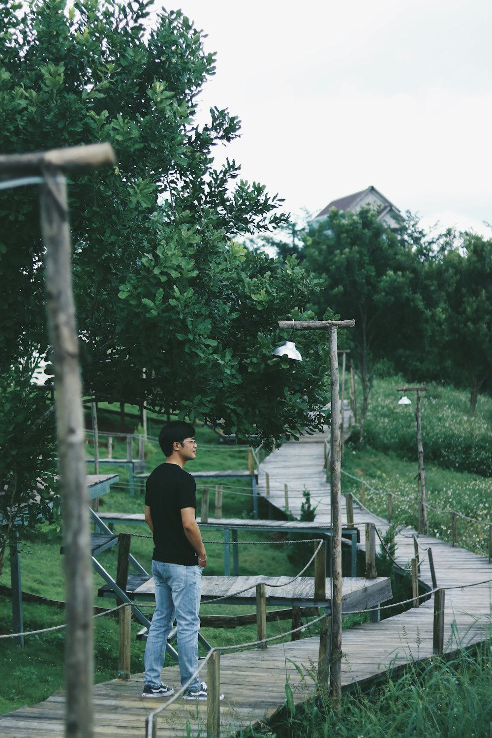 a man standing on a wooden walkway in a park