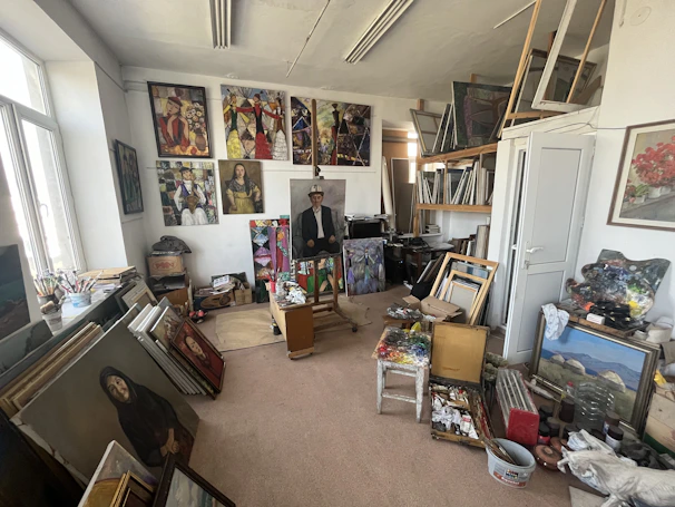 A cozy artist's studio filled with natural light, brushes, and vibrant paintings in progress.