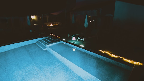 Evening shot of a pool illuminated with warm lights, creating a cozy atmosphere.