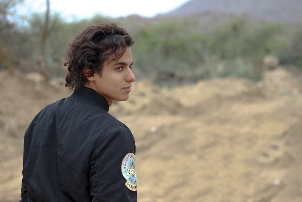 a man in a black jacket is standing in the dirt