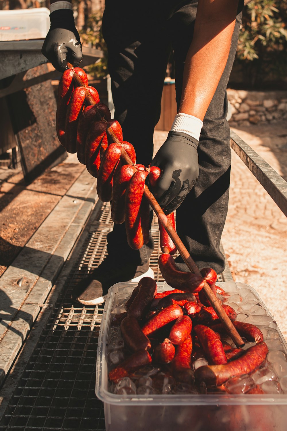 a person in black gloves holding a skewer of hot dogs