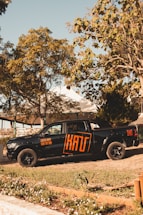 A bright orange and black company truck parked outside a rustic Wyoming workshop.