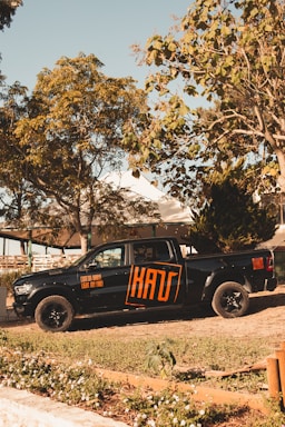 A bright orange and black company truck parked outside a rustic Wyoming workshop.