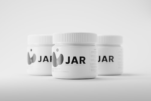 Three white jars with ribbed lids are arranged on a light background. The jars are labeled with the text 'JAR' accompanied by a minimalist graphic logo. They appear to be mockup templates for product design presentation.