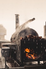 a man standing next to a large oven on top of a roof