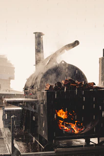 An artisan smoker in action, flames licking the wood chips as smoke curls into the evening air