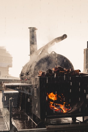 A large 1000-gallon smoker glowing with fire inside, set against a black background with yellow accents.