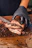 A skilled butcher expertly slicing meat with a sharp knife in a rustic kitchen setting.