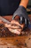 A skilled butcher expertly slicing meat with a sharp knife in a rustic kitchen setting.