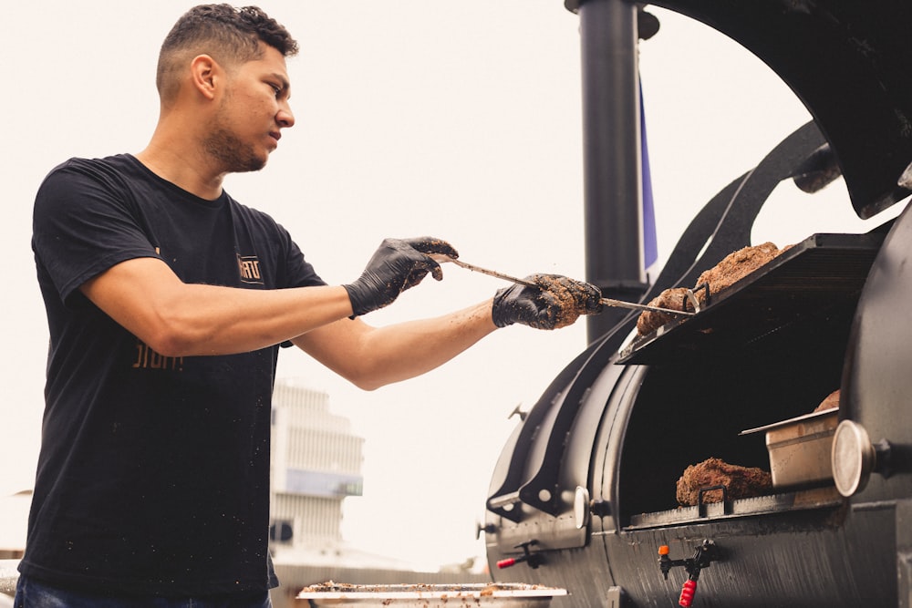 a man in a black shirt is grilling some food