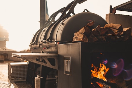 Smokin Gunns BBQ food truck parked at a sunny outdoor festival with smoke rising from the charcoal offset smoker.
