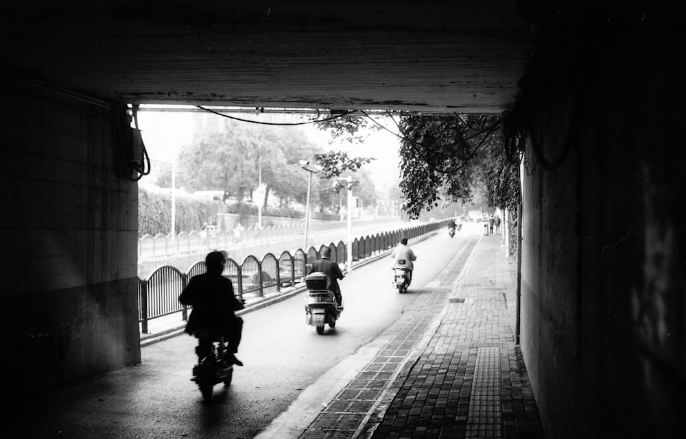 a black and white photo of people riding scooters