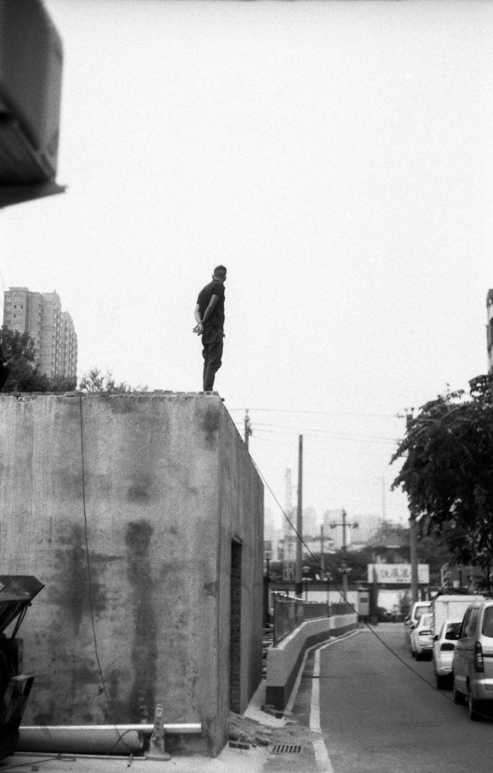 a black and white photo of a man standing on top of a building