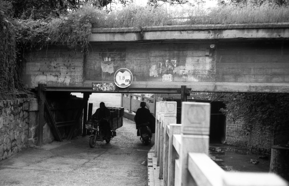 a black and white photo of two people riding bikes