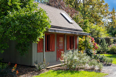 A cozy granny flat with large windows and warm wooden accents nestled in a garden.
