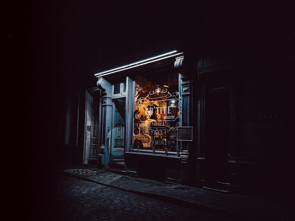a dark street with a store front lit up at night