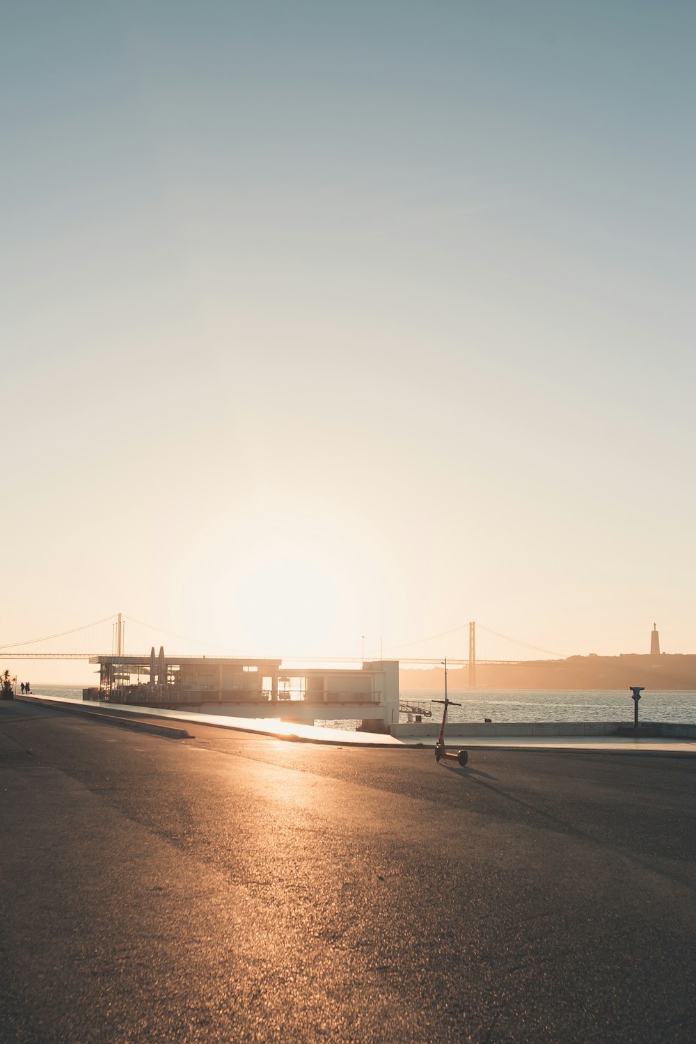 the sun is setting over the water near a bridge