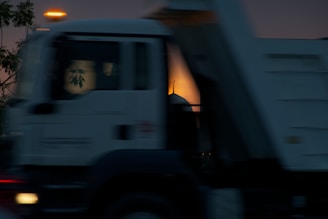 Moving truck driving through Abu Dhabi city streets at sunset.