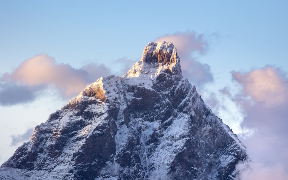 a snow covered mountain with clouds in the background