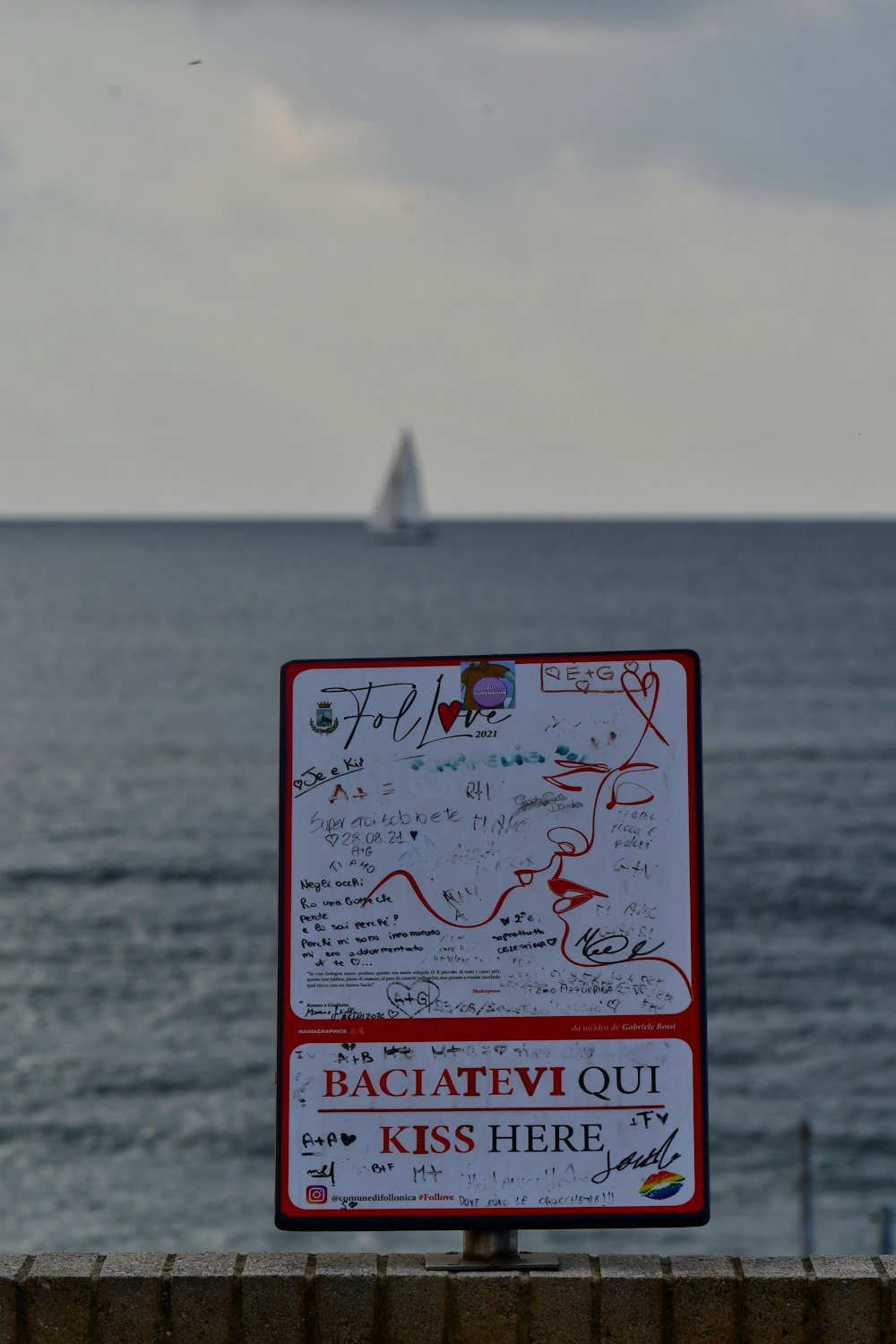 a red and white sign sitting on top of a wooden fence