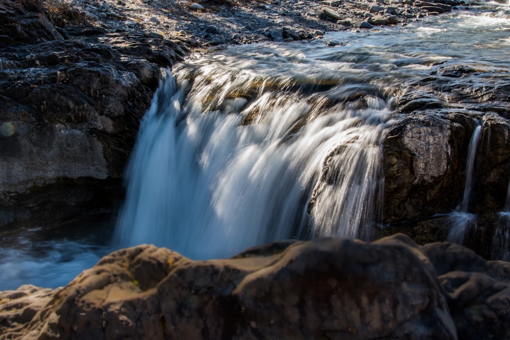 a small waterfall flowing over rocks into a body of water