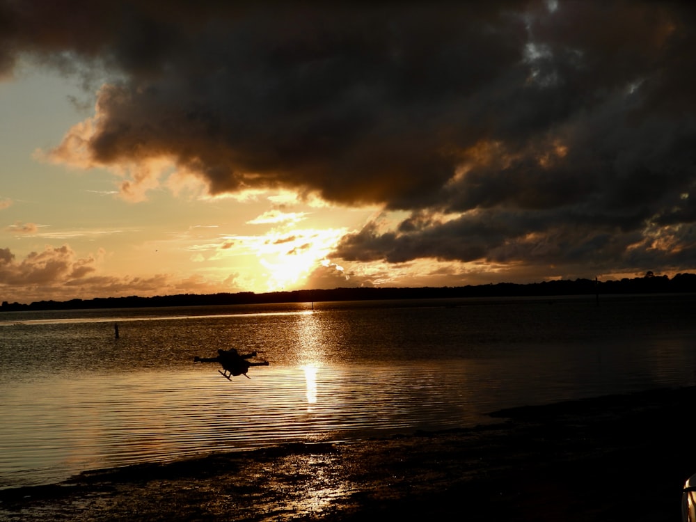 a boat floating on top of a lake under a cloudy sky