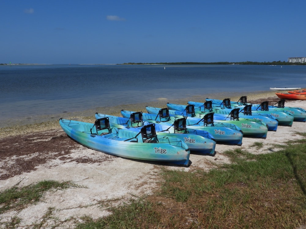 a row of blue kayaks sitting on top of a sandy beach