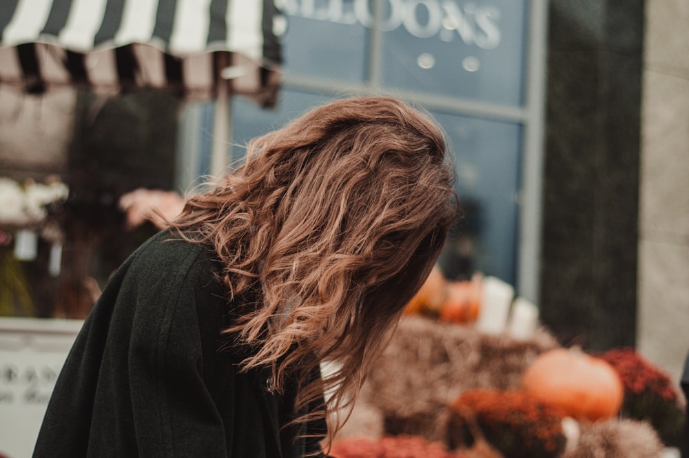 a woman with long hair walking down a street