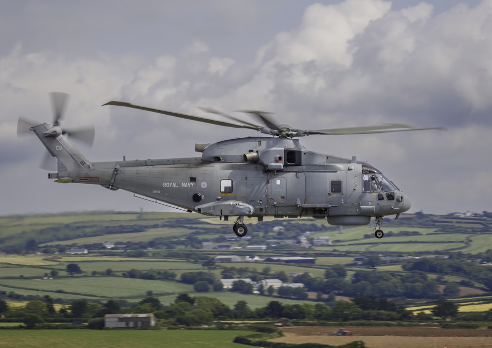 a large helicopter flying over a lush green field