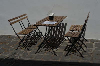 A neatly arranged set of foldable chairs and a compact table ready for outdoor use on a sunny day.