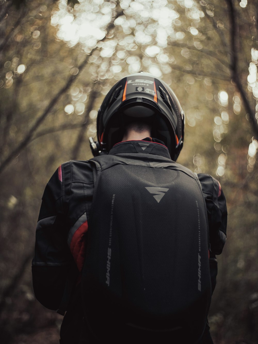 a man with a helmet on walking through a forest