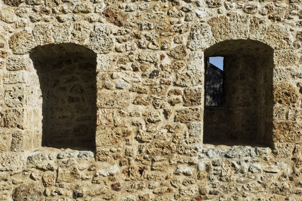 two windows in a stone wall with a blue sky in the background