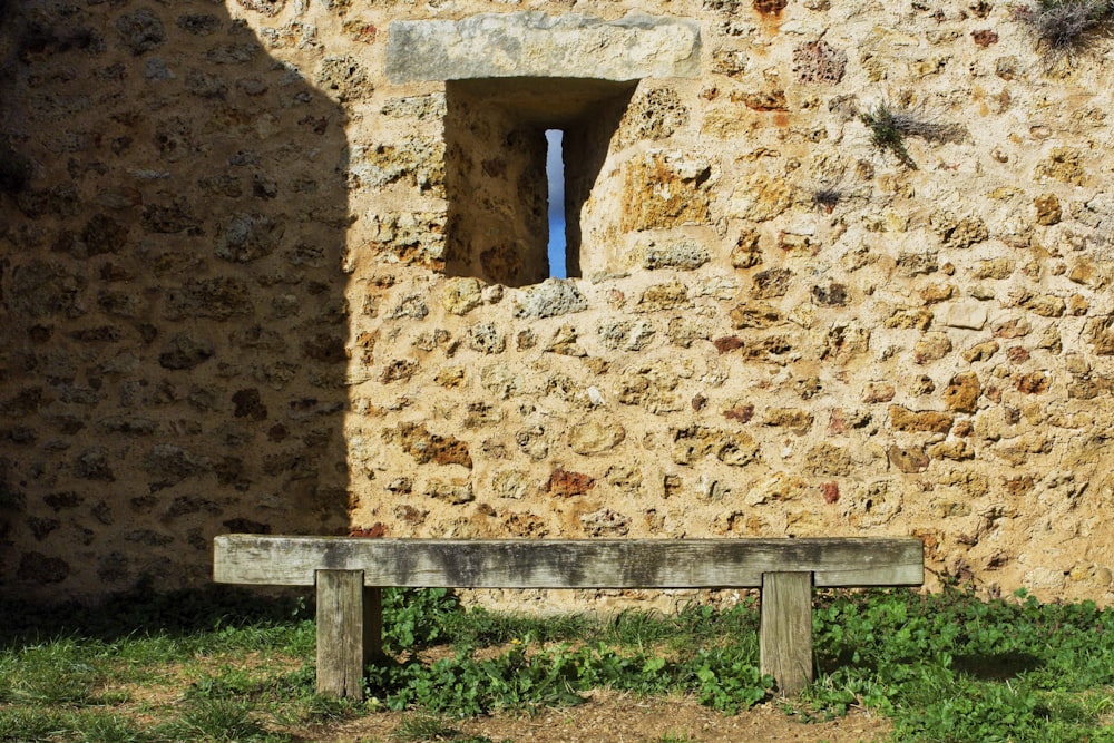 a wooden bench sitting in front of a stone building