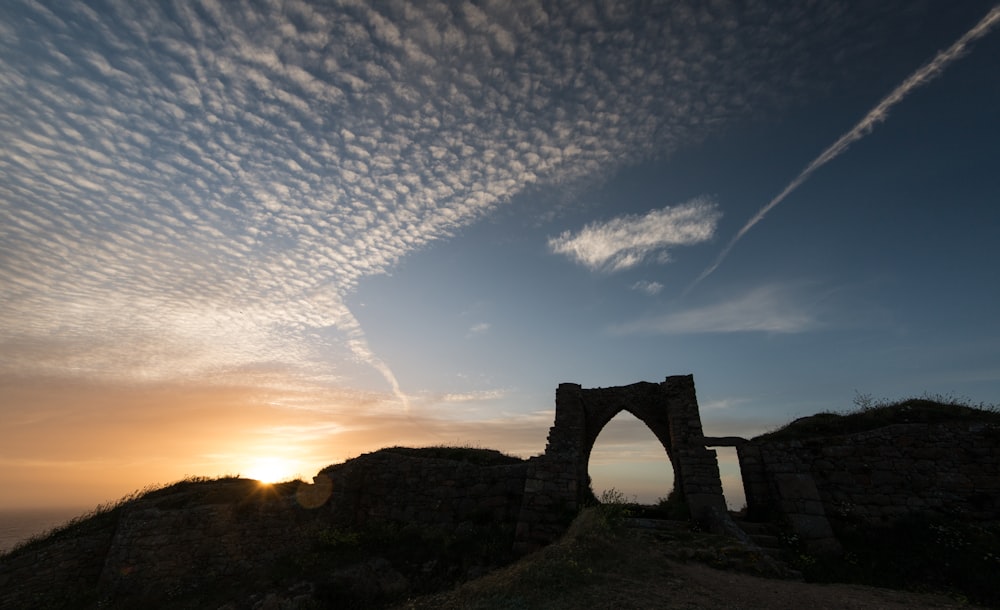 the sun is setting over the ruins of a castle