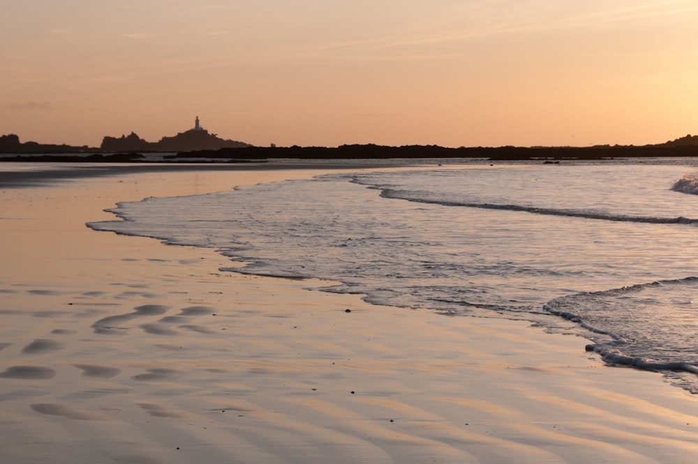 the sun is setting over the water at the beach