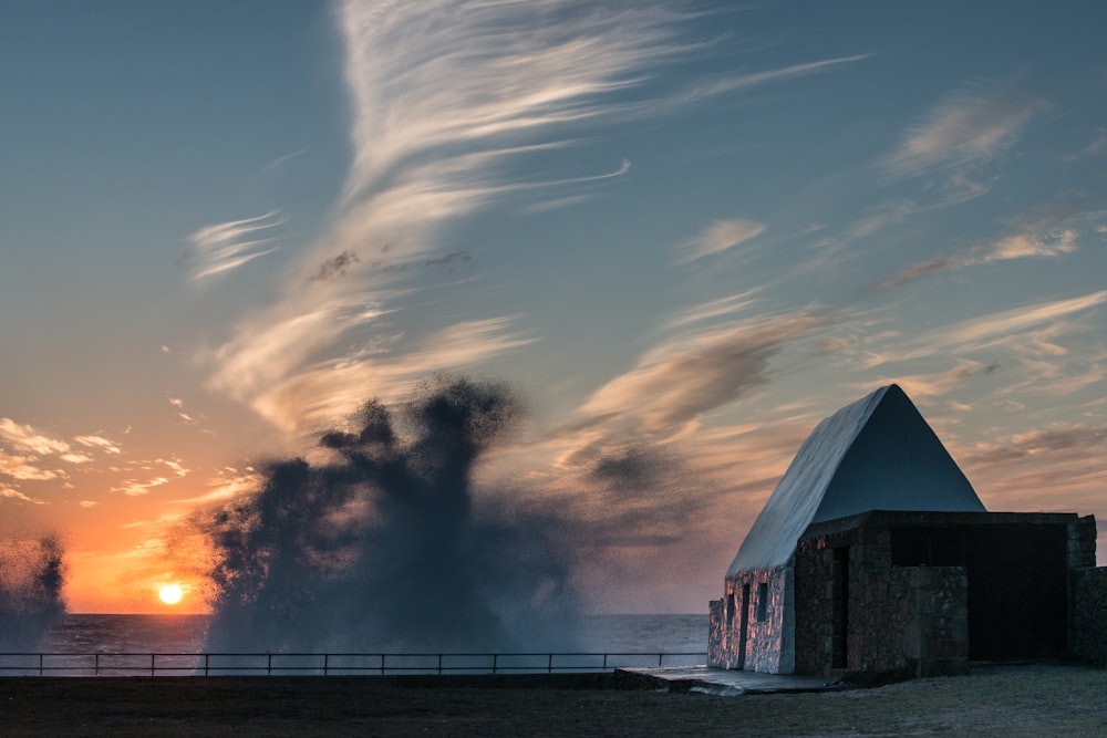 the sun is setting over the ocean with smoke coming out of it