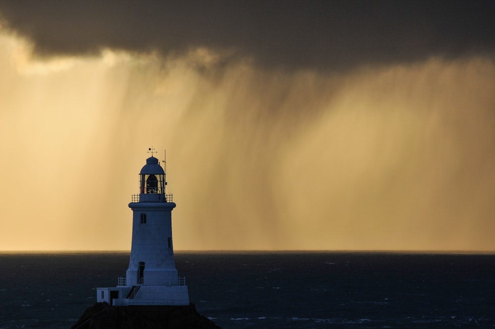 a lighthouse in the middle of the ocean under a storm