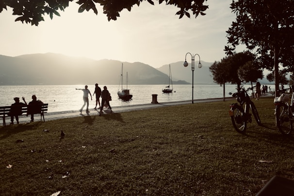 Seniors smiling warmly as they enjoy a serene lakeside sunset on a guided tour.