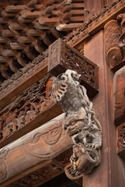 Intricate wooden carvings adorn the structure, depicting mythical creatures and intricate patterns. The craftsmanship includes detailed reliefs and ornate designs that showcase traditional architectural artistry.