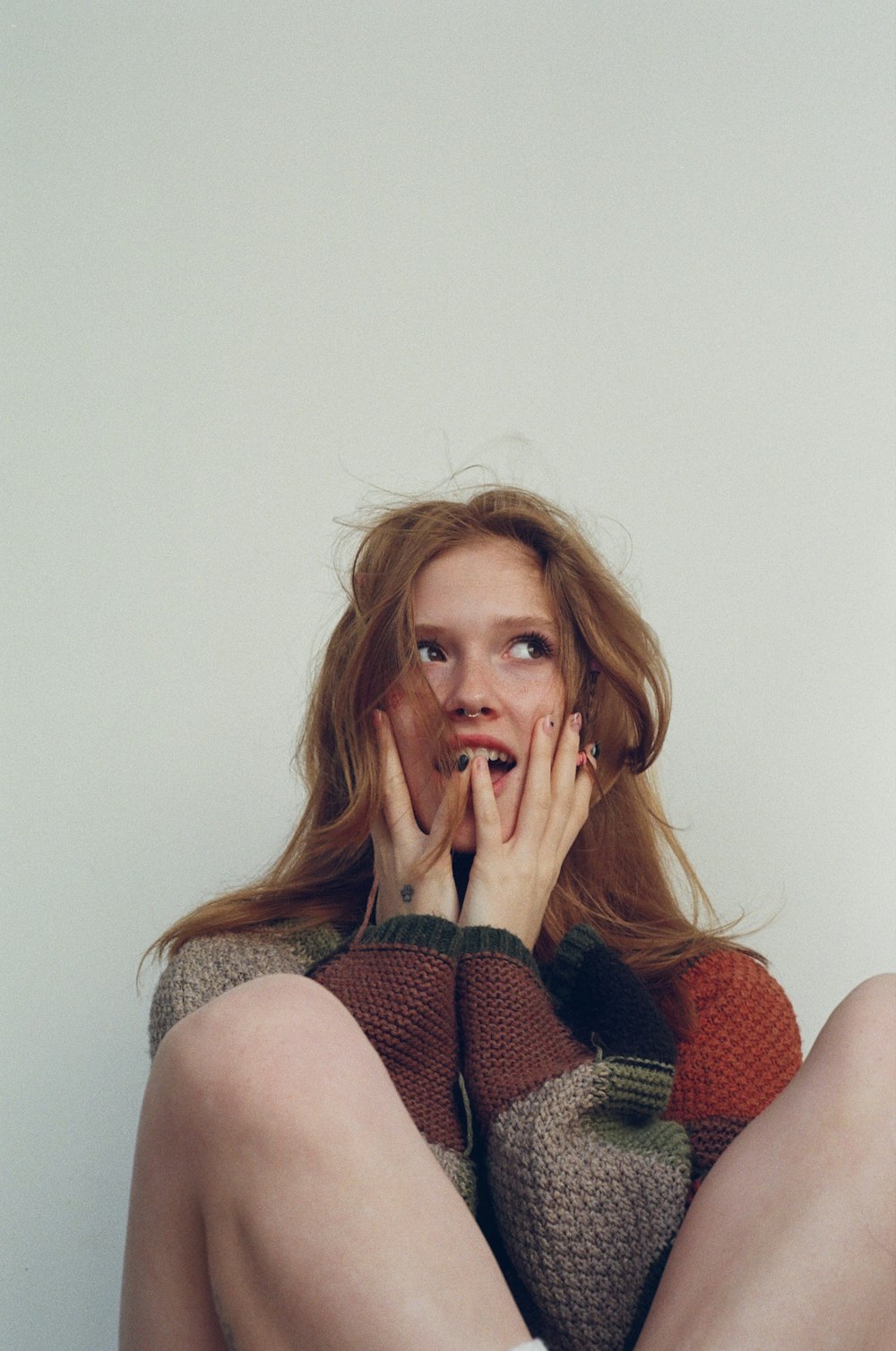 a woman sitting on the floor with her hands on her face