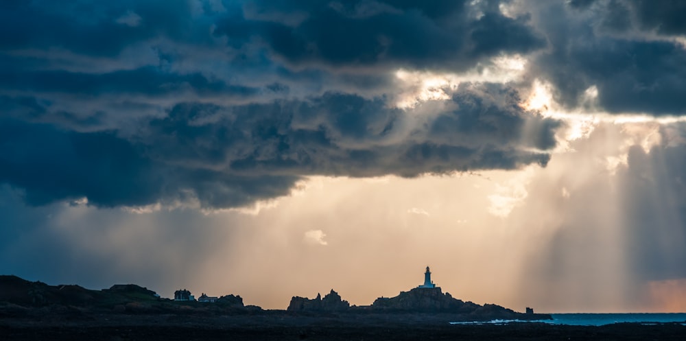 the sun shines through the clouds over a lighthouse